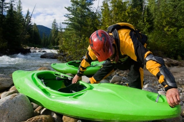 A whitewater kayaker prepares his boat at the put in of a high mountain creek.