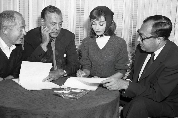 2. (Centro) La actriz Audrey Hepburn firmando contrato para la producción Love in the Afternoon. Foto - Getty Images