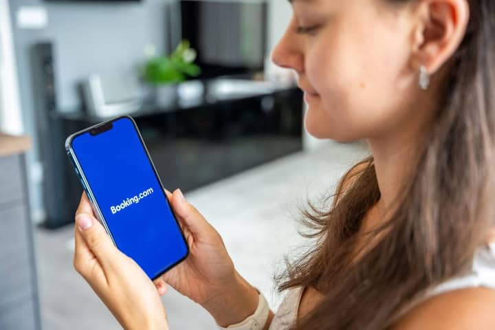 3. Mujer mirando Booking.com en su celular. Foto - Alamy