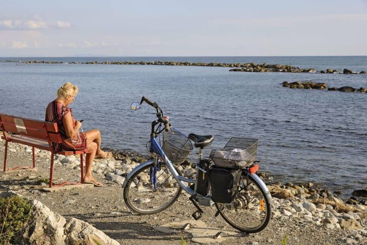 1. Mujer con bicicleta frente el mar de la Toscana, Italia. Foto - Alamy