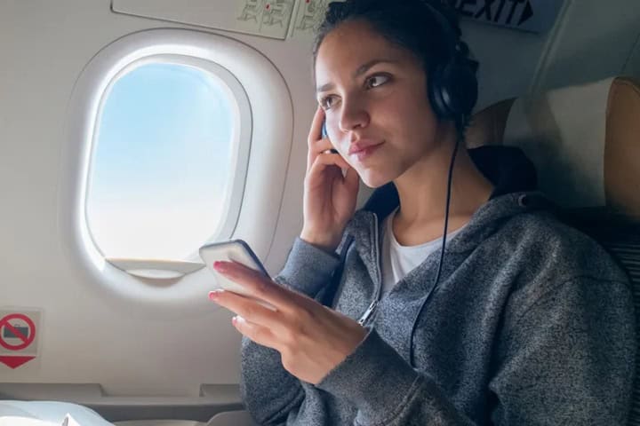 6. Mujer escuchando música en avión. Foto - Qthzb