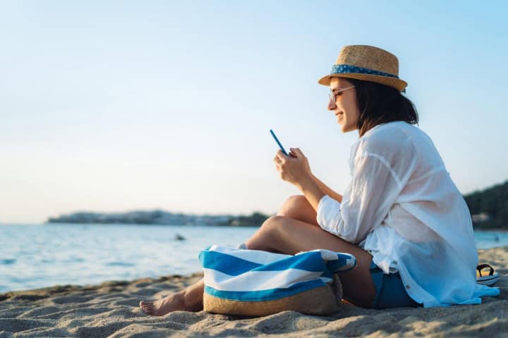1. Mujer en la playa con celular. Foto -Getty Images