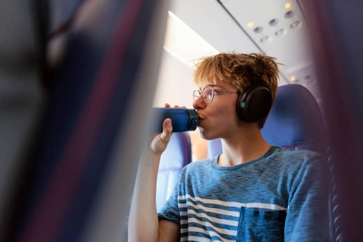 11. Viajero tomando agua en avión. Foto - GettyImages (Jet Lag)