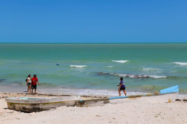 12. Visitantes jugando en la playa de Chuburná. Foto - Alamy
