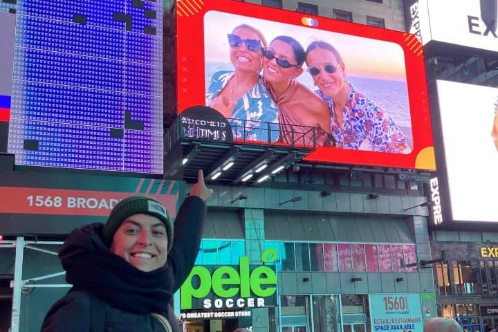 6. Visitante señalando su foto en pantalla de Times Square. Foto - Book Your Tour