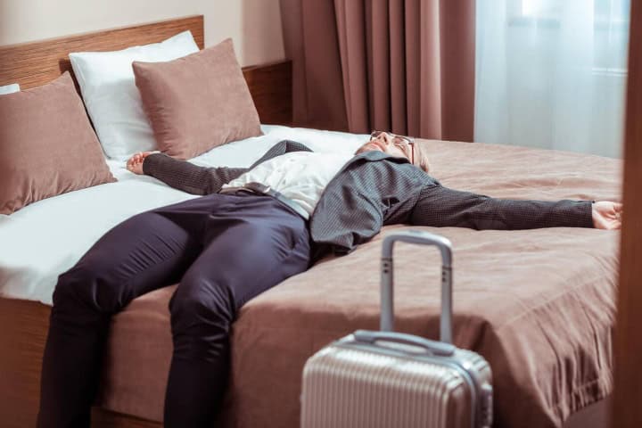 1. Hombre tomando un descanso junto a una maleta. Foto - Alamy