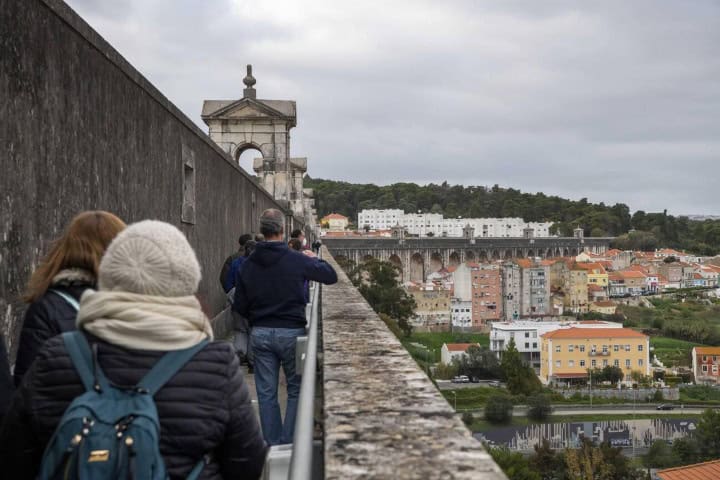 1. Viajeros caminando en el Acueducto de Lisboa. Foto - Alamy