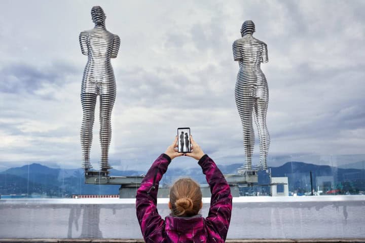 7. Viajera fotografiando las estatuas de Alí y Nino. Foto - Alamy