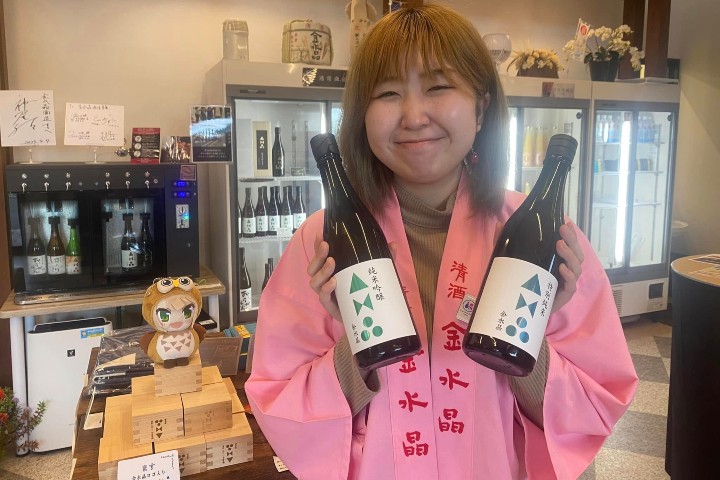 1. Mujer con botellas de sake. Foto - 福島市唯一の蔵元 金水晶酒造店（Kinsuisho) (Kinsuisho, la única cervecería en la ciudad de Fukushima) (Facebook)