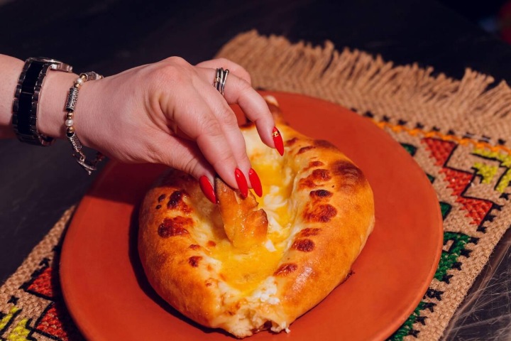 EXTRA. Mano tomando khachapuri. Foto - Alamy